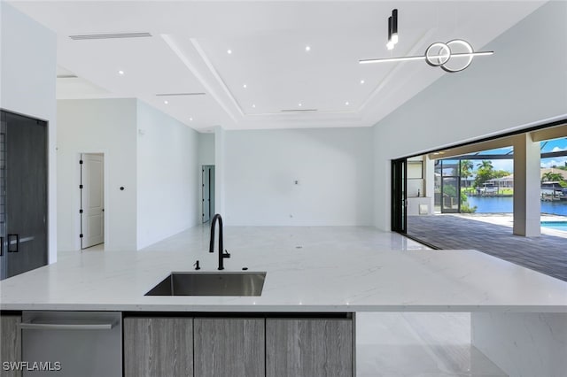 kitchen with light stone countertops, a kitchen island with sink, stainless steel dishwasher, sink, and a water view