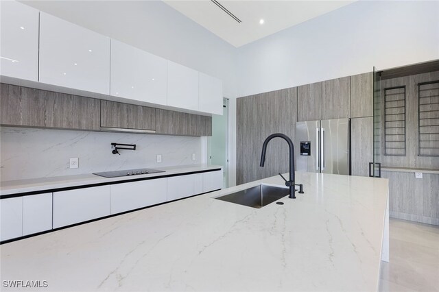 kitchen with white cabinetry, sink, light stone countertops, and stainless steel fridge with ice dispenser