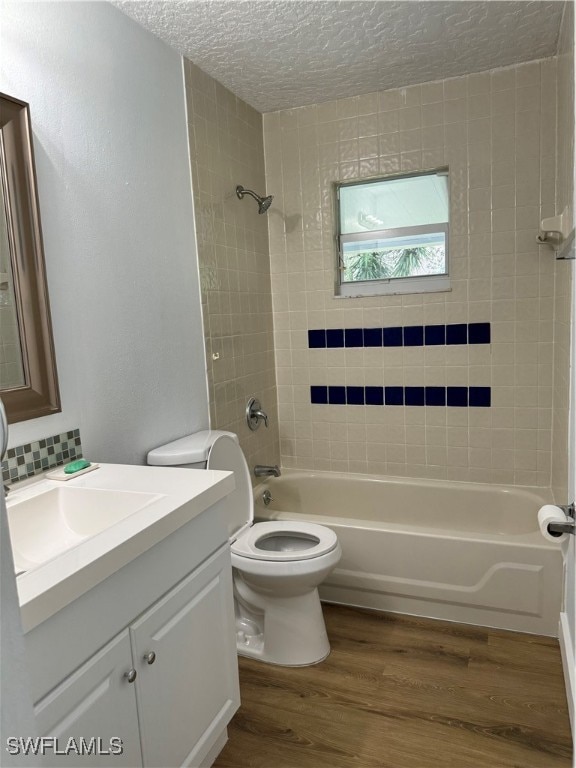 full bathroom with wood-type flooring, tiled shower / bath, vanity, and toilet