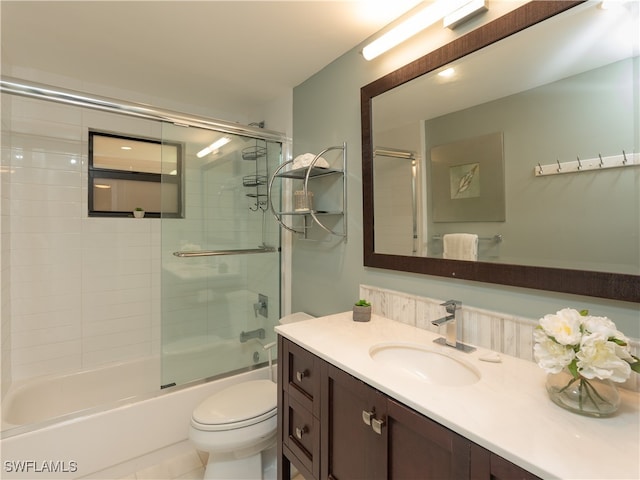 full bathroom with combined bath / shower with glass door, vanity, toilet, and tile patterned flooring