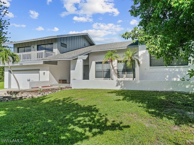 rear view of property with a yard, a garage, and a balcony