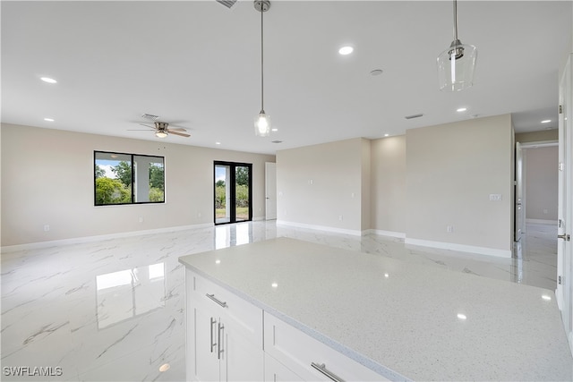 kitchen featuring light stone countertops, ceiling fan, hanging light fixtures, and white cabinetry