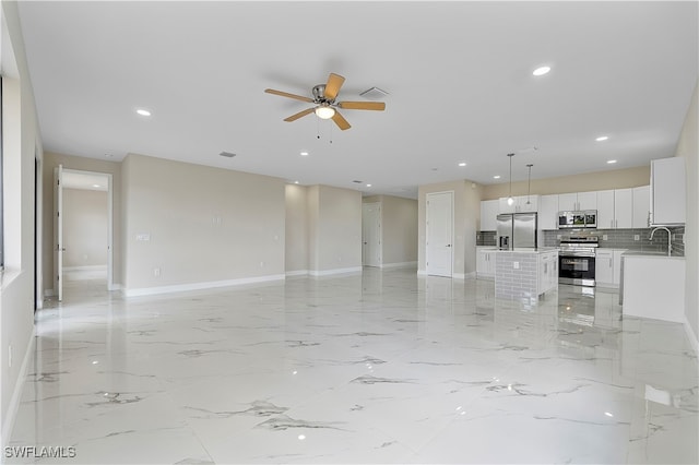 unfurnished living room featuring ceiling fan and sink