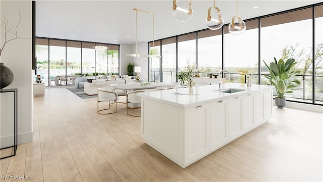 750 Goodlette-Frank Rd N Unit 202, Naples, FL 34102 - kitchen featuring white cabinetry, sink, floor to ceiling windows, pendant lighting, and light wood-type flooring