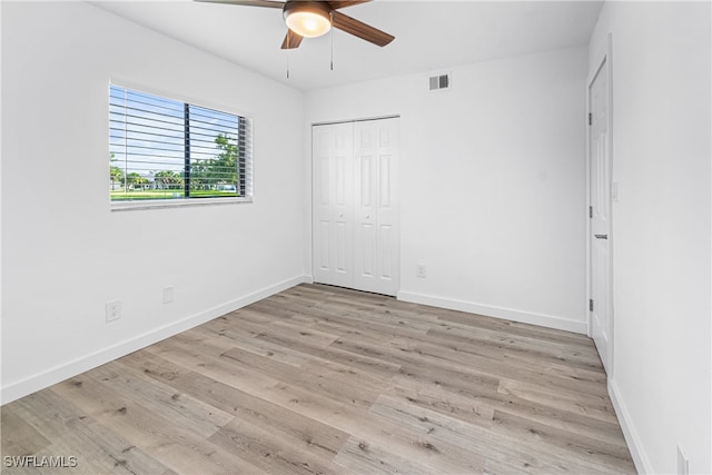 unfurnished bedroom with ceiling fan, light wood-type flooring, and a closet