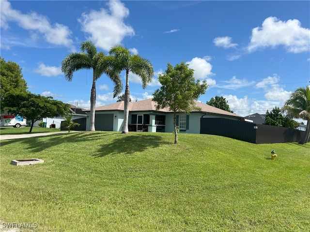 ranch-style home featuring a front lawn, an attached garage, and fence