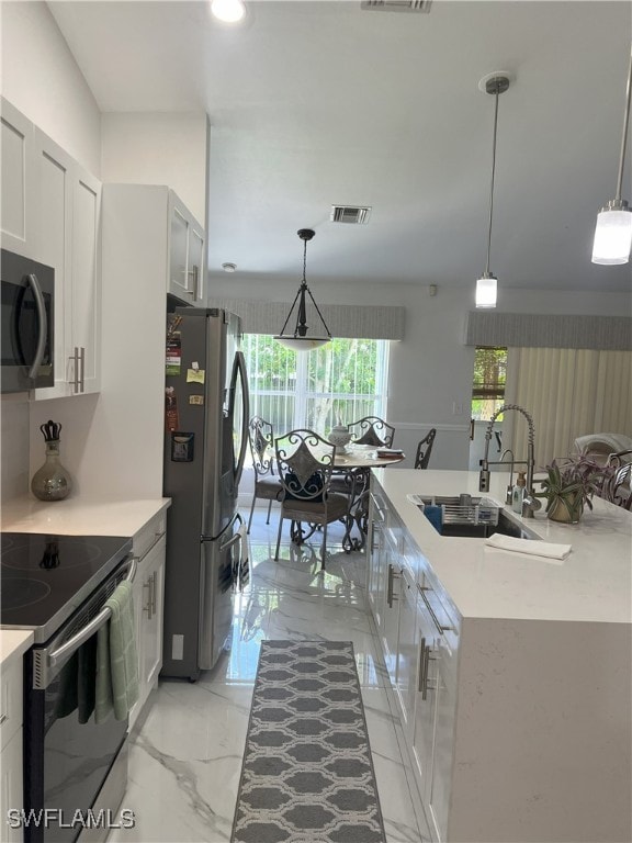 kitchen with appliances with stainless steel finishes, decorative light fixtures, and sink