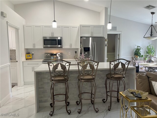 kitchen featuring a kitchen island, backsplash, appliances with stainless steel finishes, hanging light fixtures, and lofted ceiling