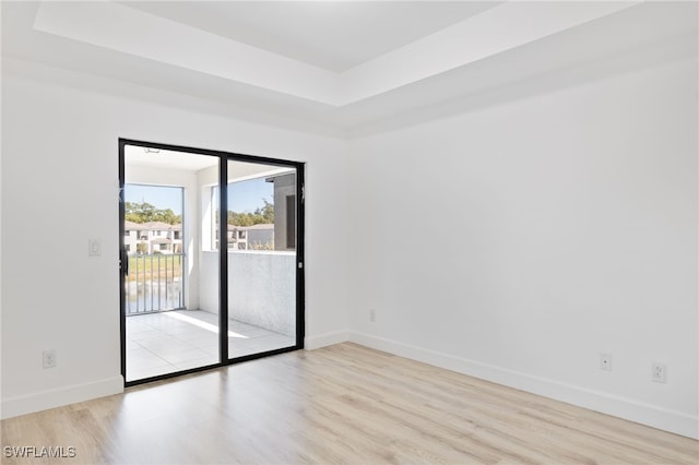 unfurnished room with light hardwood / wood-style floors and a raised ceiling