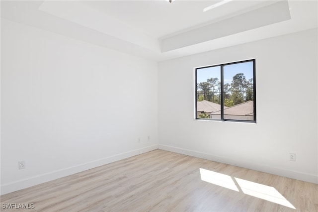 unfurnished room featuring a raised ceiling and light hardwood / wood-style flooring