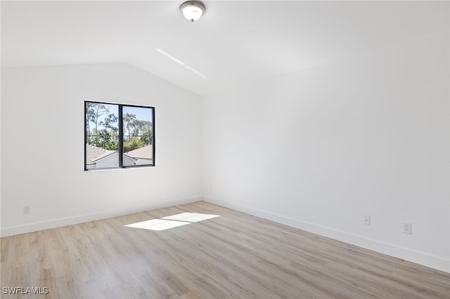 spare room with light hardwood / wood-style floors and lofted ceiling