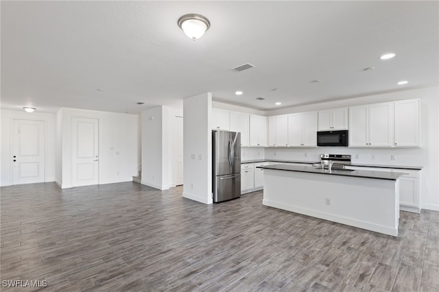 kitchen with white cabinets, appliances with stainless steel finishes, light hardwood / wood-style flooring, and an island with sink