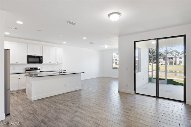 kitchen with appliances with stainless steel finishes, a center island with sink, white cabinetry, and sink