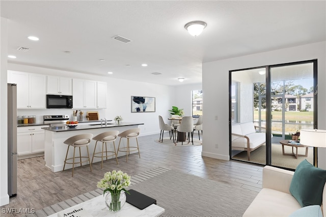 kitchen featuring visible vents, appliances with stainless steel finishes, white cabinets, and a breakfast bar area