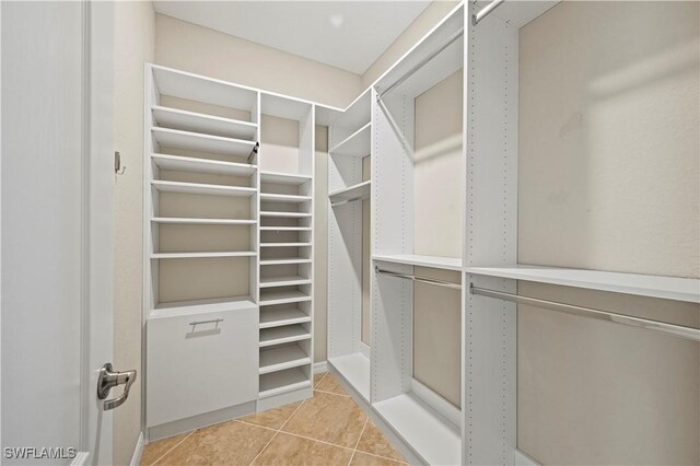 walk in closet with light tile patterned floors