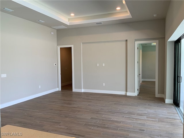 unfurnished bedroom featuring light wood-type flooring and a raised ceiling