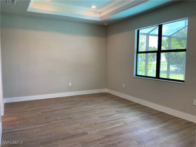 spare room with a tray ceiling and hardwood / wood-style floors