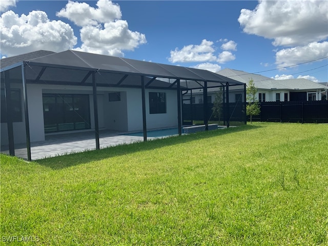 back of house with a lanai, a patio area, and a yard