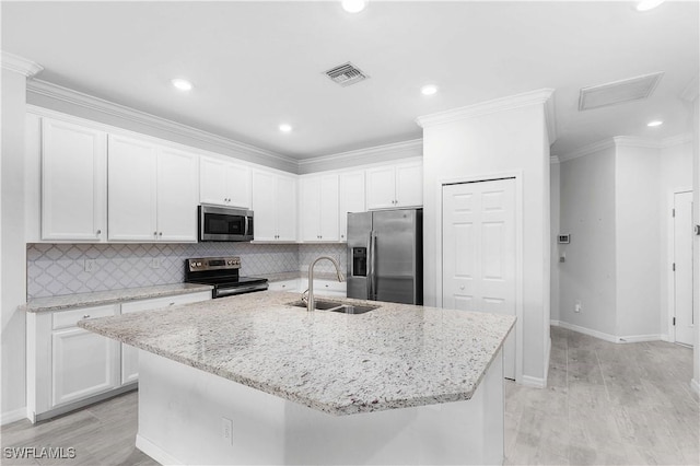 kitchen with appliances with stainless steel finishes, a kitchen island with sink, and white cabinets