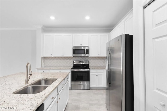 kitchen with appliances with stainless steel finishes, sink, backsplash, white cabinets, and light stone counters