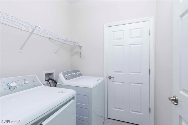 clothes washing area featuring light tile patterned flooring and washing machine and clothes dryer