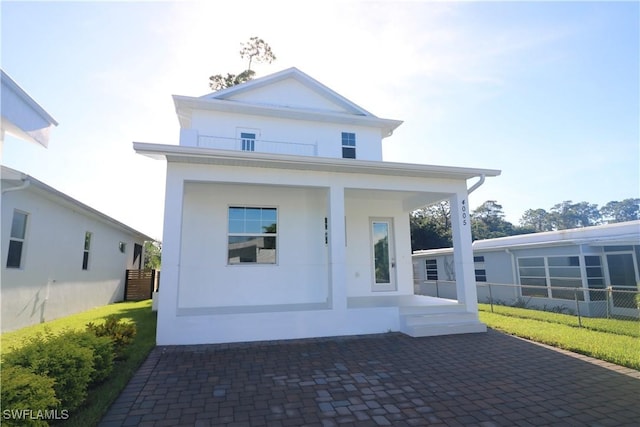 view of front of house featuring stucco siding, a porch, and fence