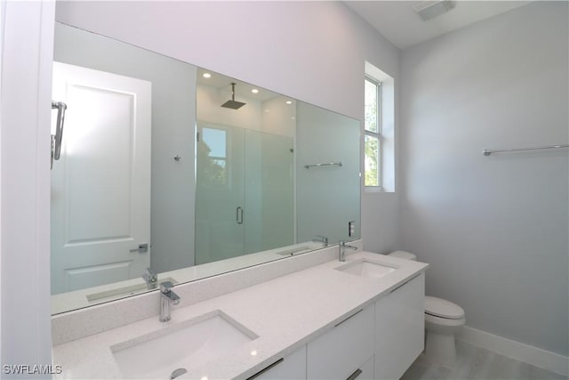 full bath with a shower stall, double vanity, and a sink