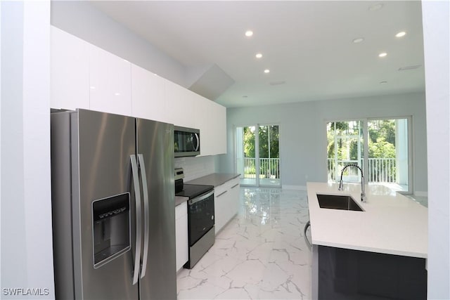 kitchen featuring marble finish floor, modern cabinets, a sink, recessed lighting, and stainless steel appliances