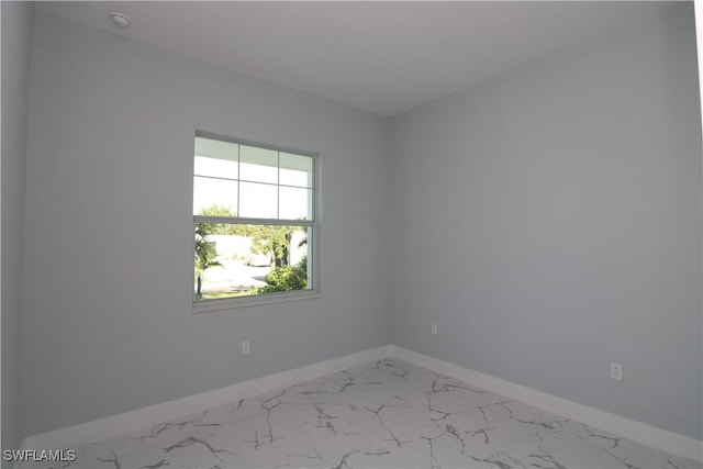 spare room featuring marble finish floor and baseboards