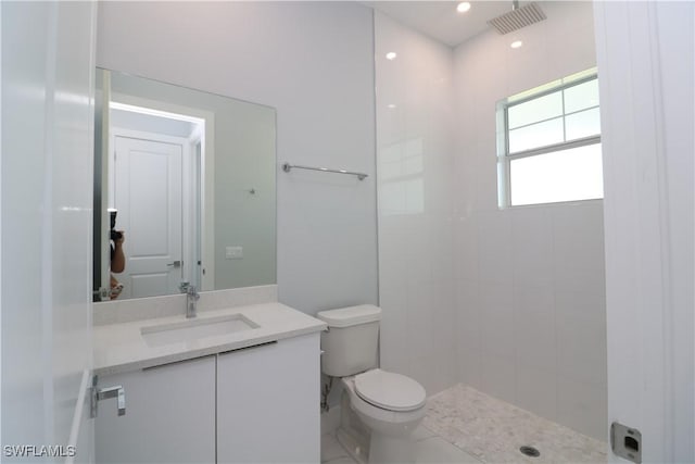 full bathroom featuring tiled shower, toilet, vanity, and visible vents