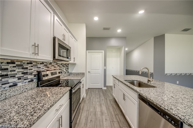 kitchen with white cabinetry, stainless steel appliances, sink, and light hardwood / wood-style floors