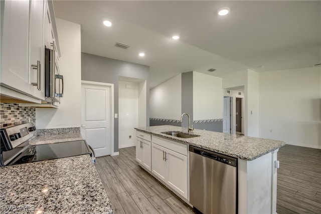 kitchen with a kitchen island with sink, stainless steel appliances, sink, white cabinetry, and light wood-type flooring