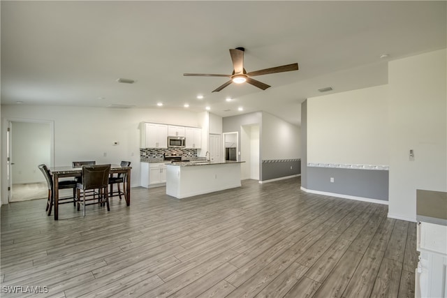 living room featuring light wood-type flooring, lofted ceiling, sink, and ceiling fan