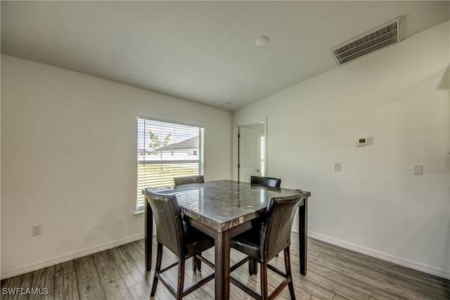 dining space with vaulted ceiling and wood-type flooring