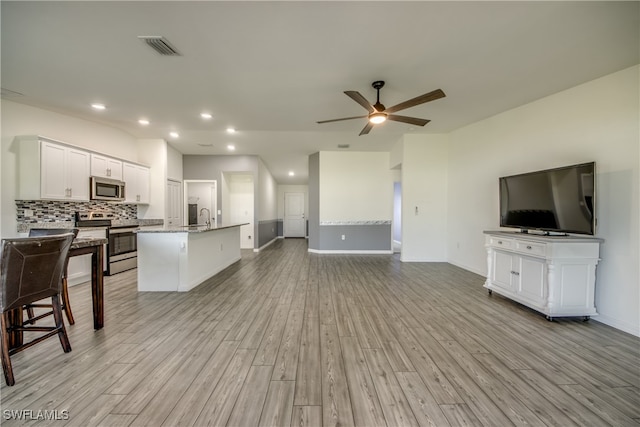 living room with light hardwood / wood-style flooring, ceiling fan, and sink