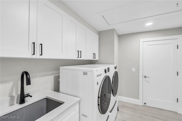 washroom with cabinet space, light wood finished floors, baseboards, independent washer and dryer, and a sink