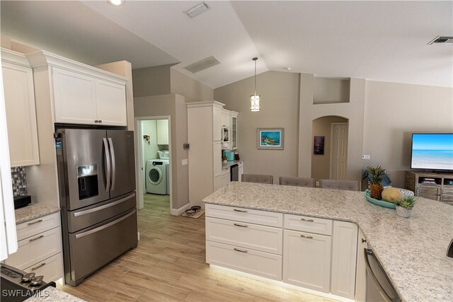 kitchen featuring washer / dryer, stainless steel fridge, visible vents, and white cabinets