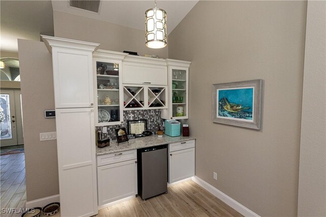 bar with light wood finished floors, baseboards, visible vents, decorative light fixtures, and fridge