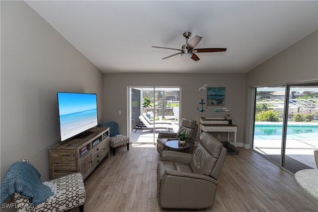 living room featuring vaulted ceiling, ceiling fan, and light wood-style floors