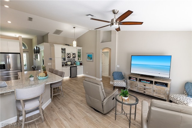 living area with arched walkways, light wood finished floors, visible vents, and a ceiling fan