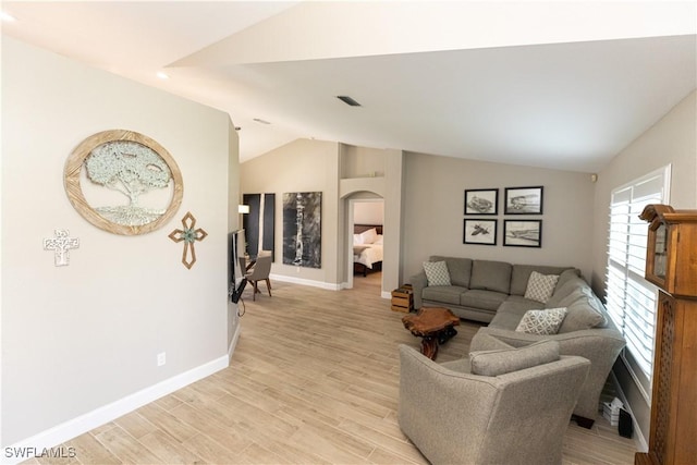 living area with lofted ceiling, visible vents, light wood-style flooring, and baseboards