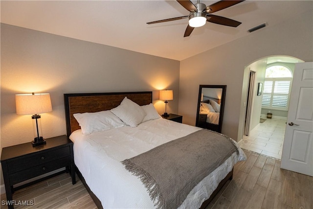 bedroom with visible vents, arched walkways, a ceiling fan, wood tiled floor, and vaulted ceiling