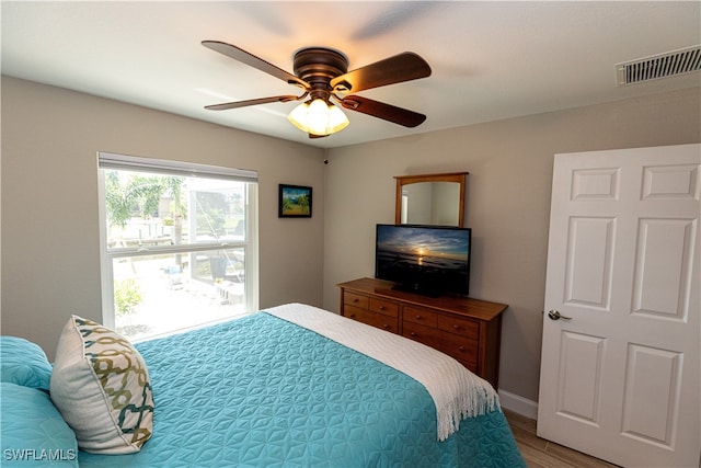 bedroom with ceiling fan, light wood finished floors, visible vents, and baseboards