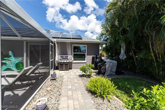 exterior space with glass enclosure, solar panels, a patio, and stucco siding