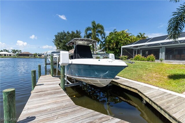 view of dock featuring a water view, boat lift, a lanai, and a lawn