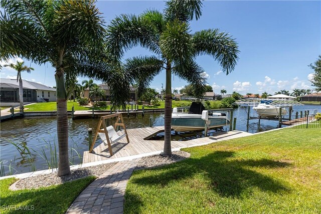 dock area featuring a water view, a lawn, and boat lift