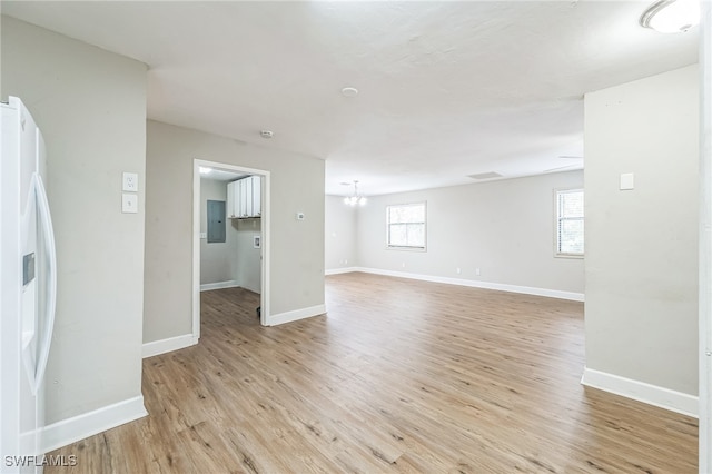 unfurnished living room with electric panel and light hardwood / wood-style floors