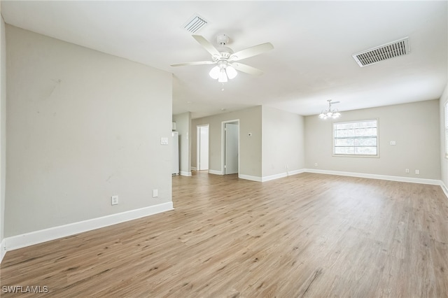 unfurnished room with ceiling fan with notable chandelier and light wood-type flooring