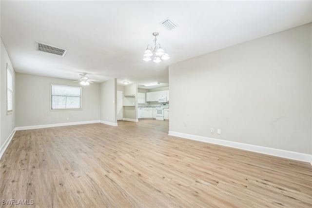 unfurnished living room with ceiling fan with notable chandelier and light hardwood / wood-style flooring