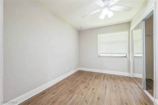 unfurnished bedroom with lofted ceiling, ceiling fan, a closet, and light wood-type flooring